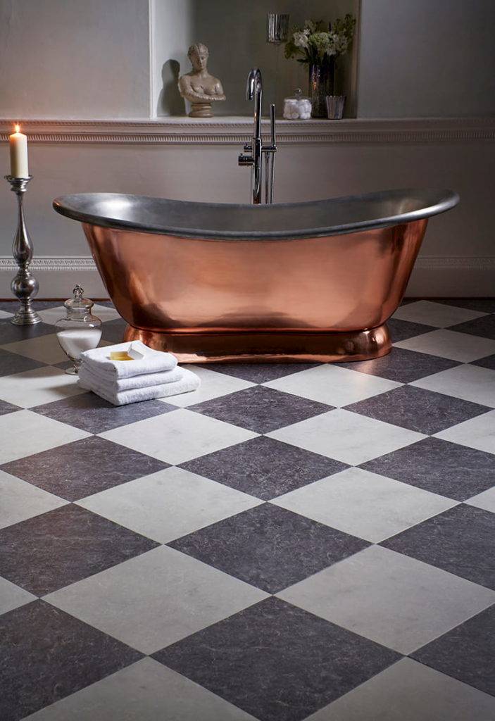 black and white chequerboard karndean flooring beneath copper bathtub in large bathroom space